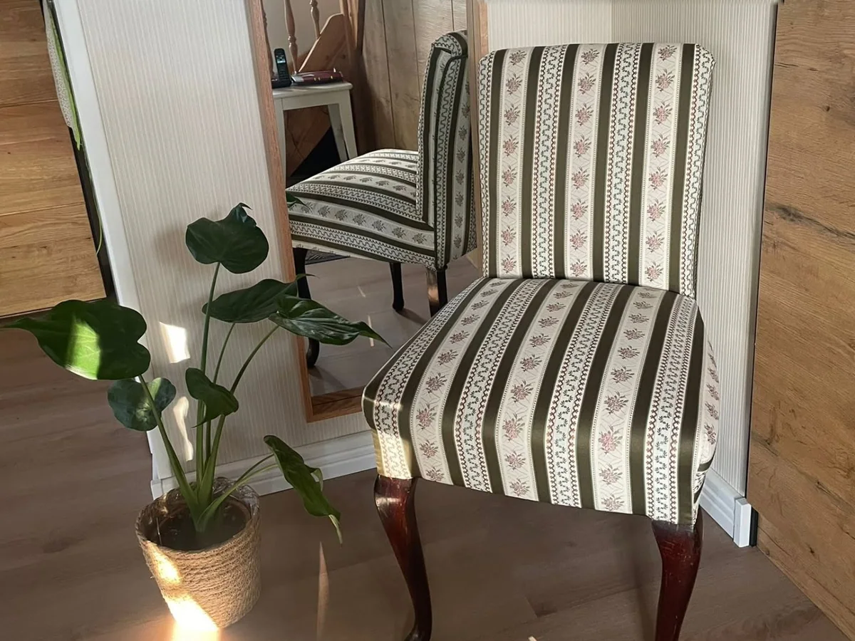 Neu bezogener Stuhl mit Streifen- und Blumenmuster vor einem Spiegel